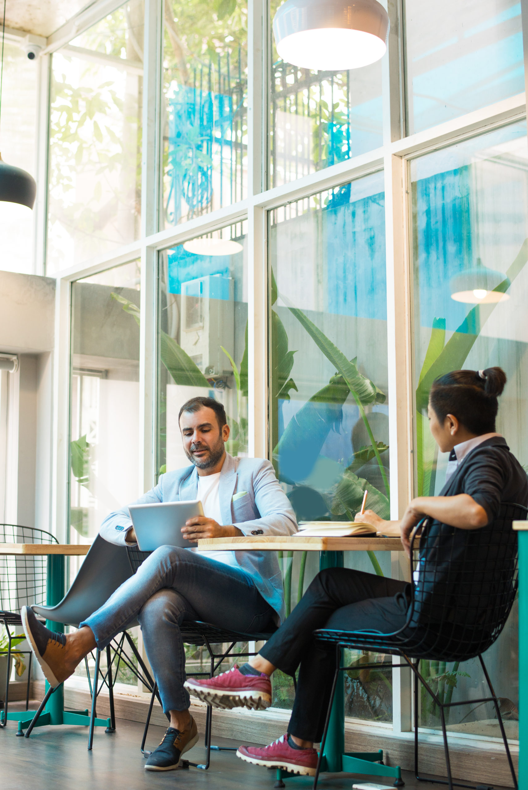 Confident multiethnic colleagues having informal meeting in cafe. Mid adult Latin American businessman and young Asian businesswoman having discussion. Interview or meeting concept